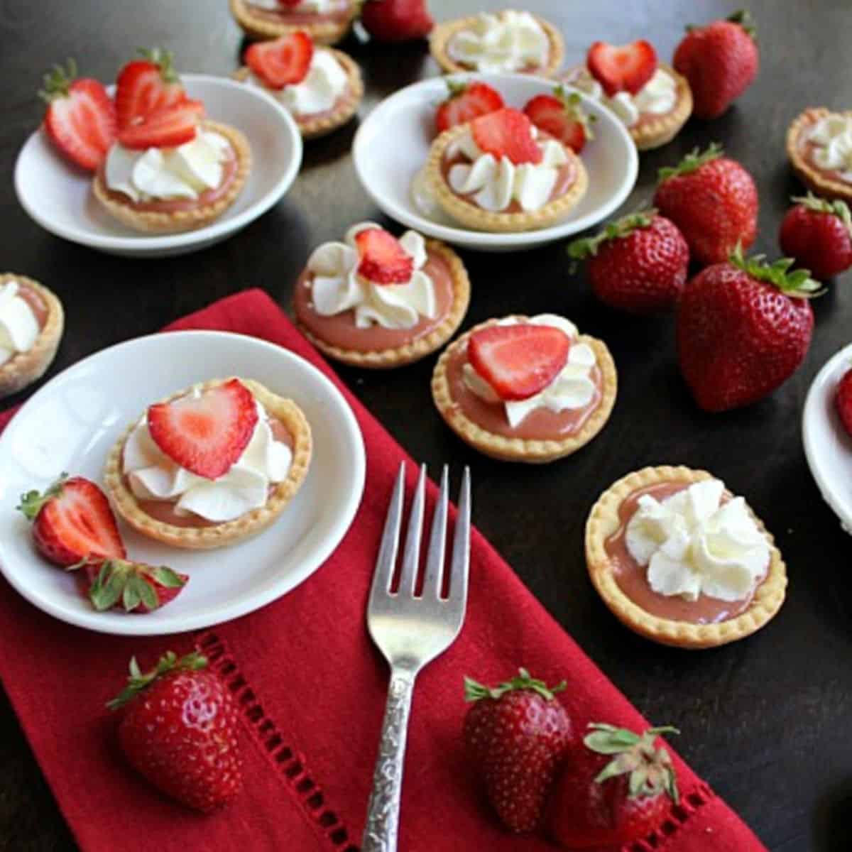 Mini strawberry tarts with strawberry curd in white bowls.
