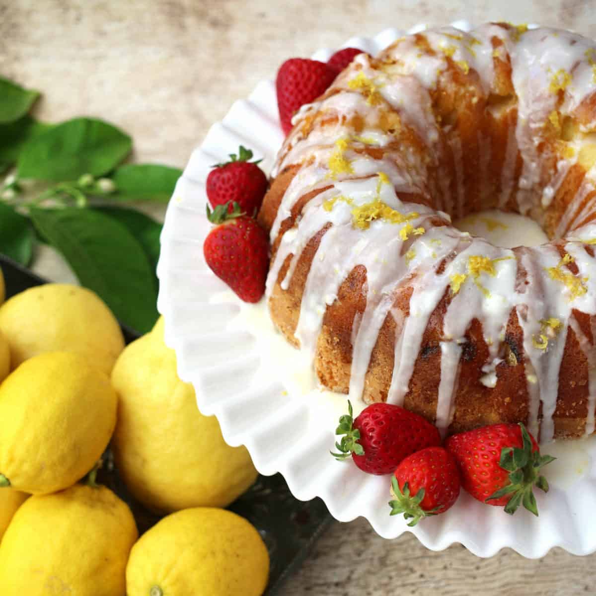 A lemon bundt cake with vanilla frosting and strawberries.