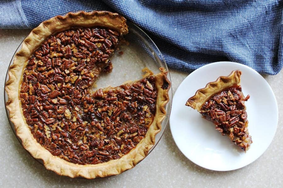 A bourbon pecan pie with a slice of pie on a white plate