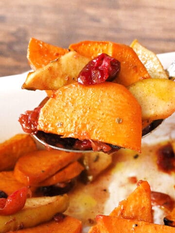 A spoonful of baked sweet potatoes with apples and cranberries.