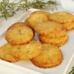 A white plate with cheese crackers and rosemary.