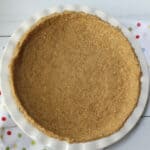 A homemade graham cracker pie crust in a white plate.