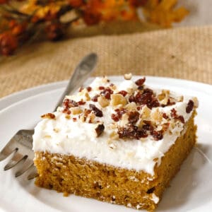 A slice of pumpkin sheet cake with white frosting.