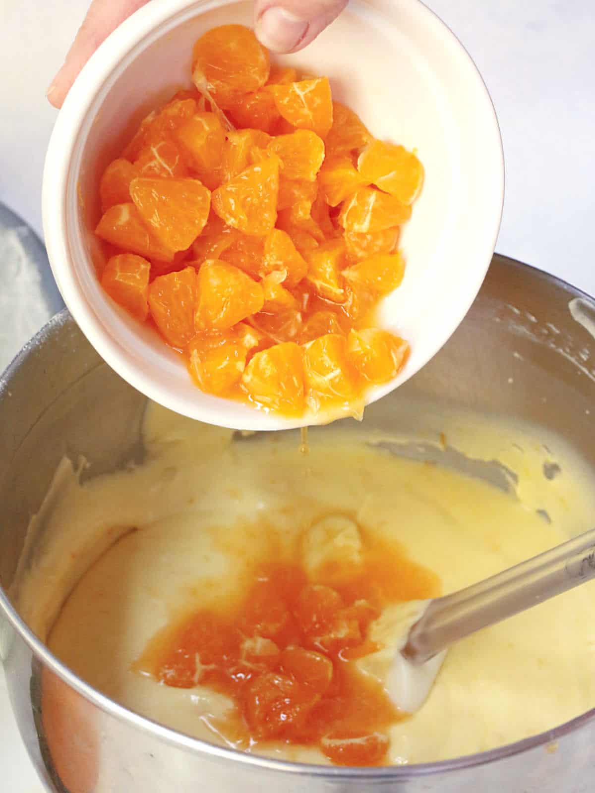 Adding oranges to a cake batter.