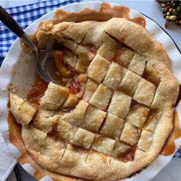 Peach pandowdy in a pie plate with a spoon.