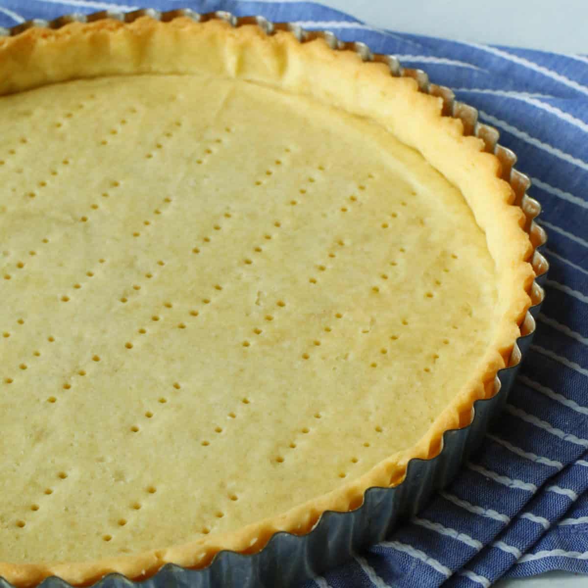 A baked tart shell on a blue towel