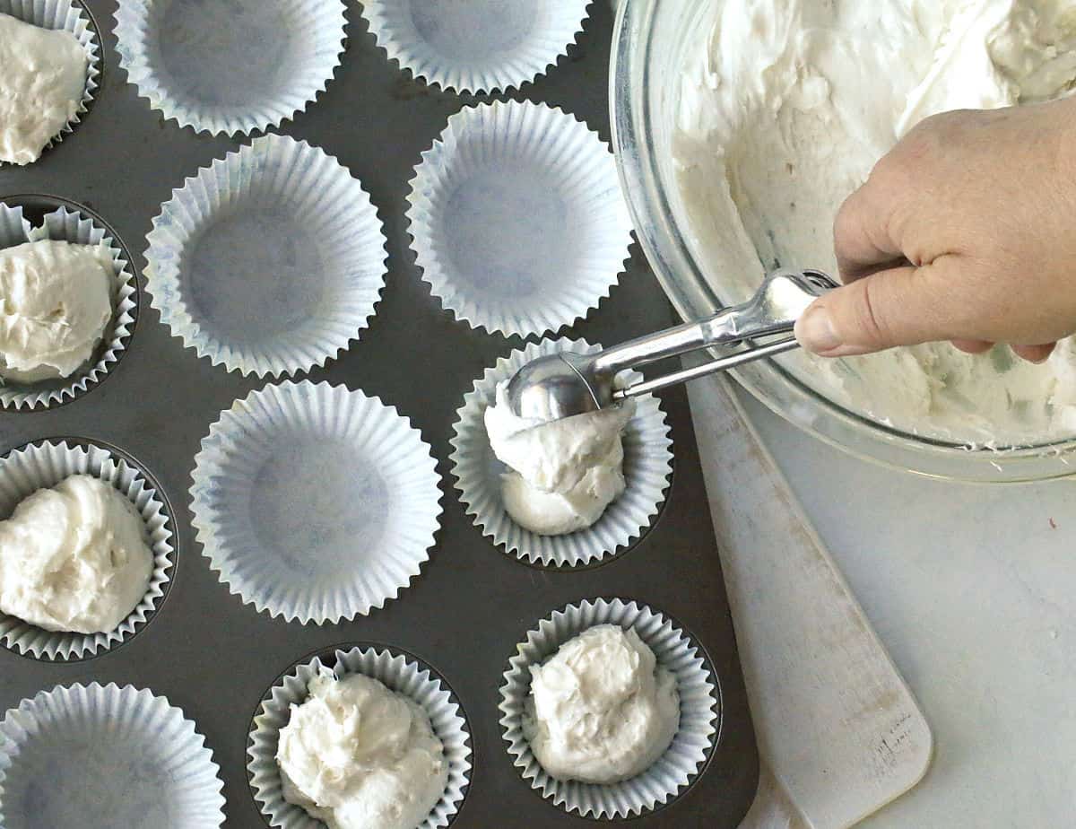 Scooping cake batters into cupcake liners.