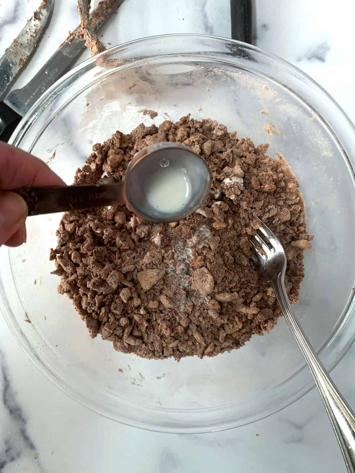 Adding cream to a chocolate dough mix.