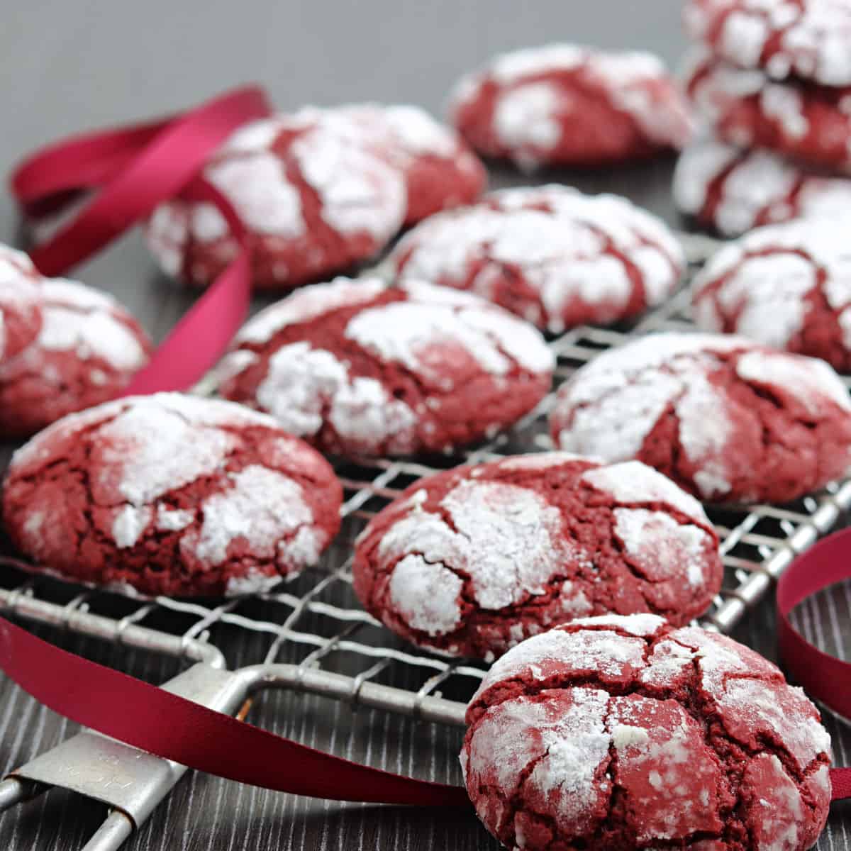 Red velvet crinkle cookies on a wire rack.