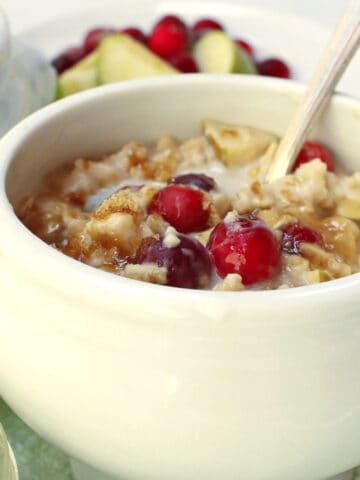 Oatmeal in a white bowl with cranberries.