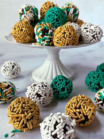 Chocolate truffles on a white pedestal, rolled in green, white and gold sprinkles