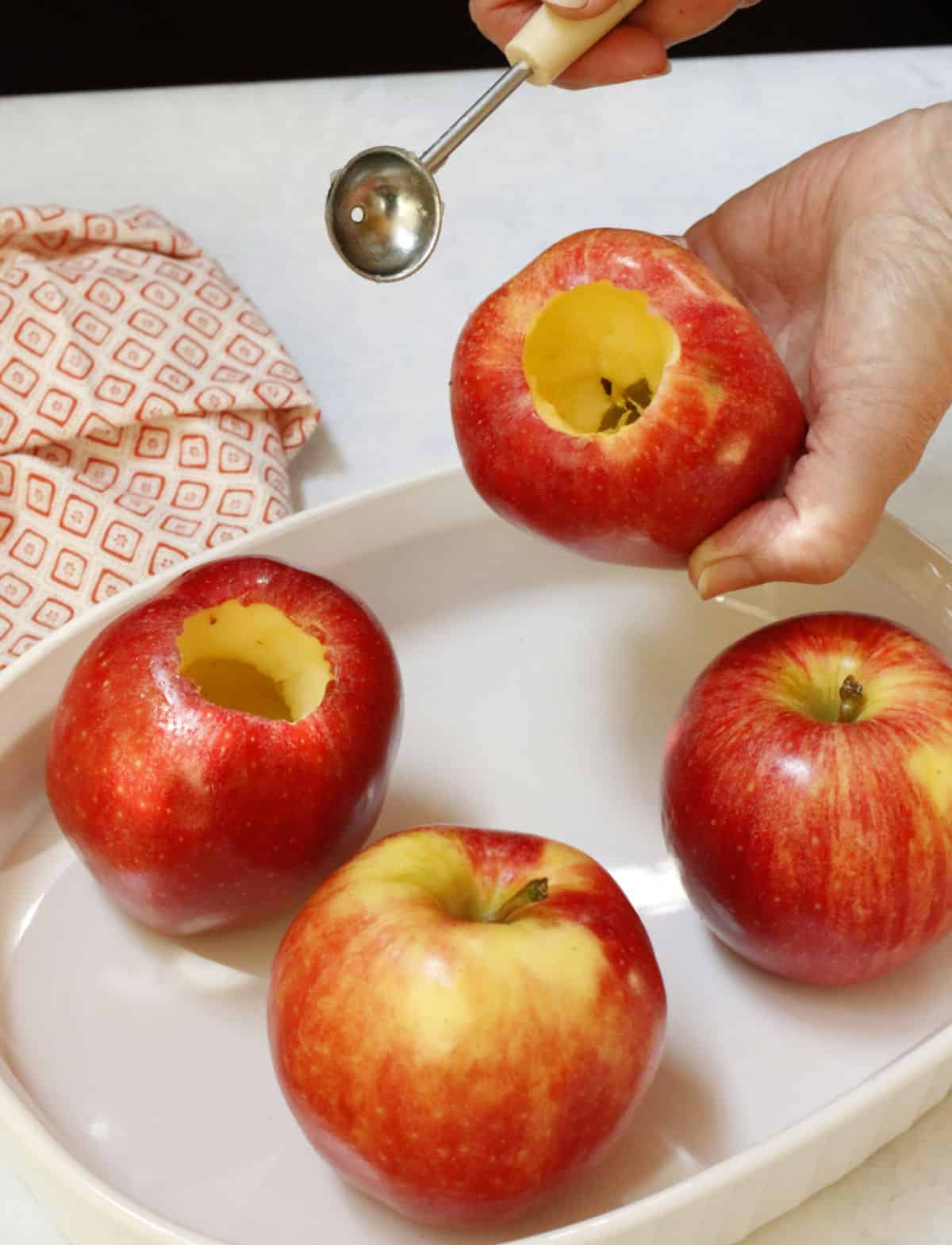 Cored apples in a white dish.