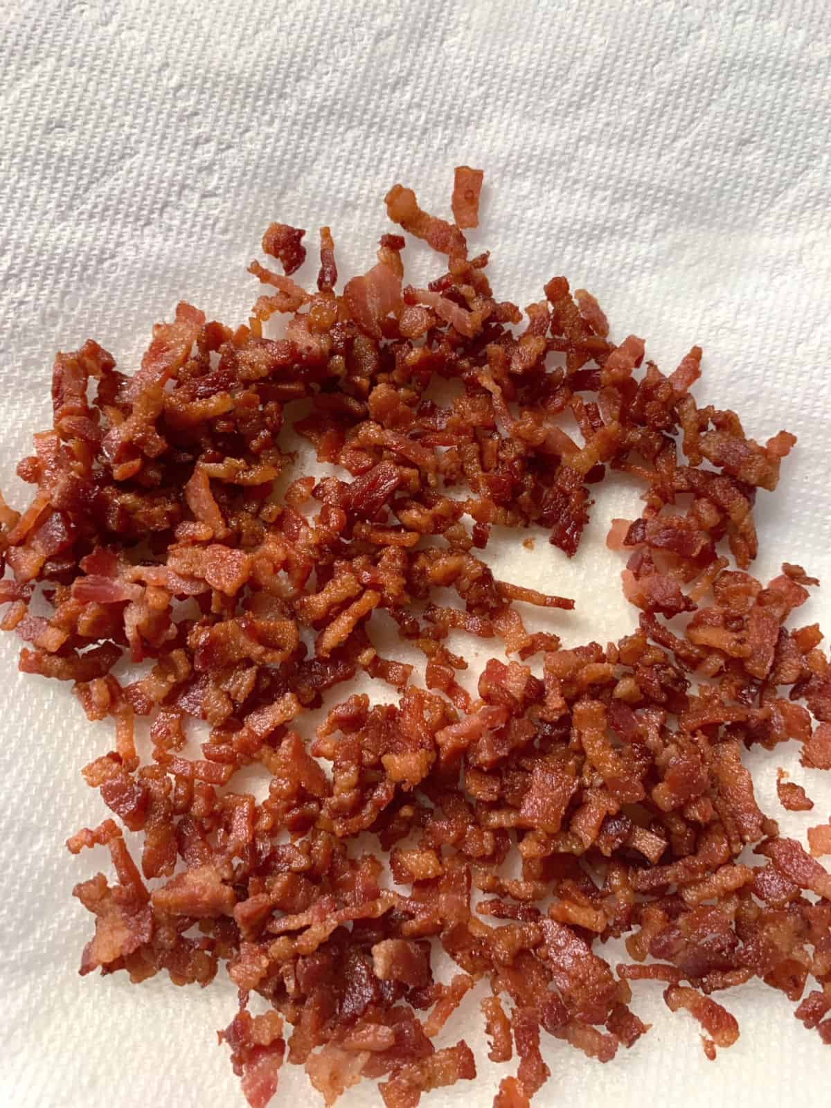 Cooked chopped bacon on a paper towel.