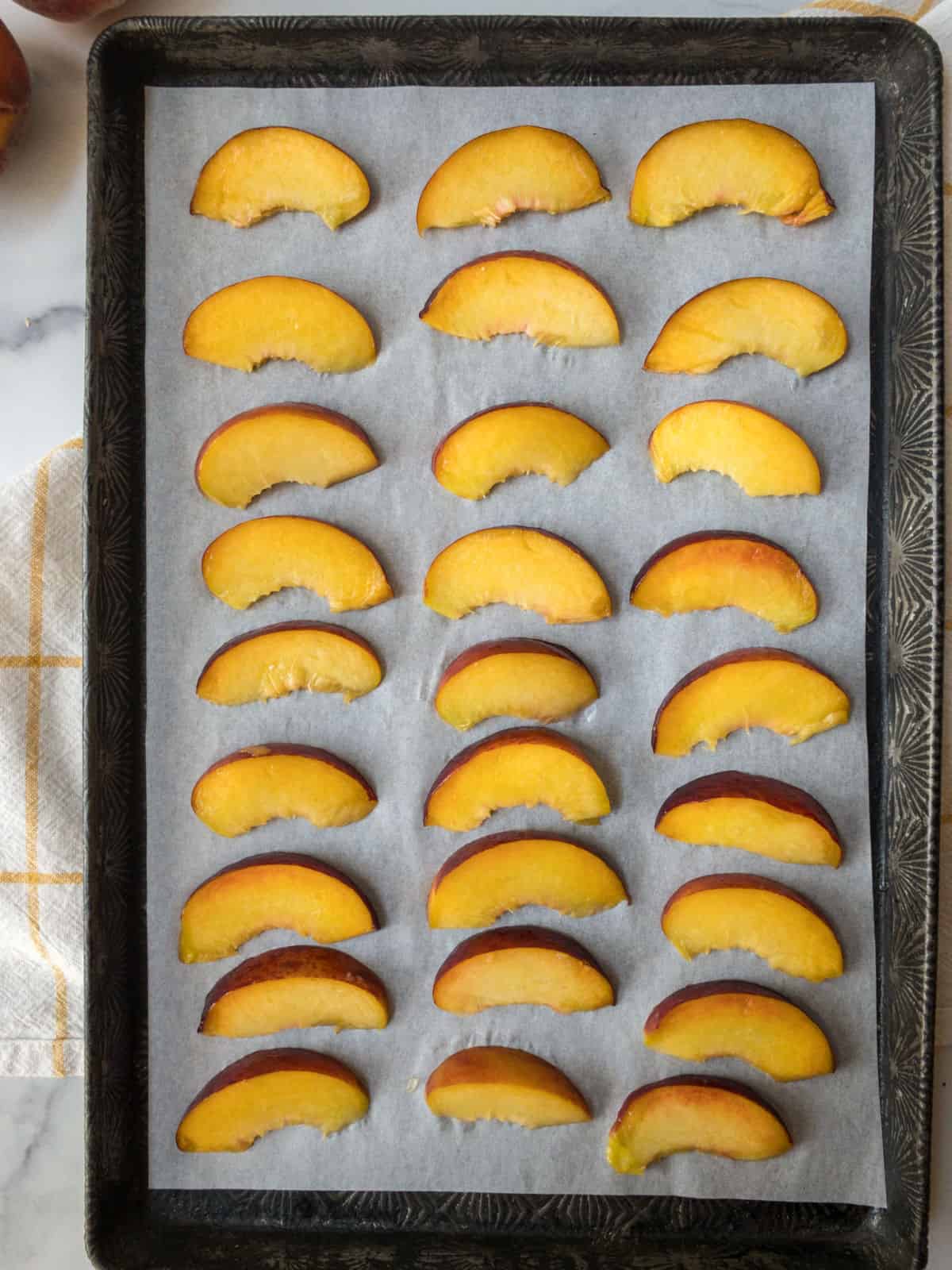 Slices of fresh peaches on a cookie sheet.