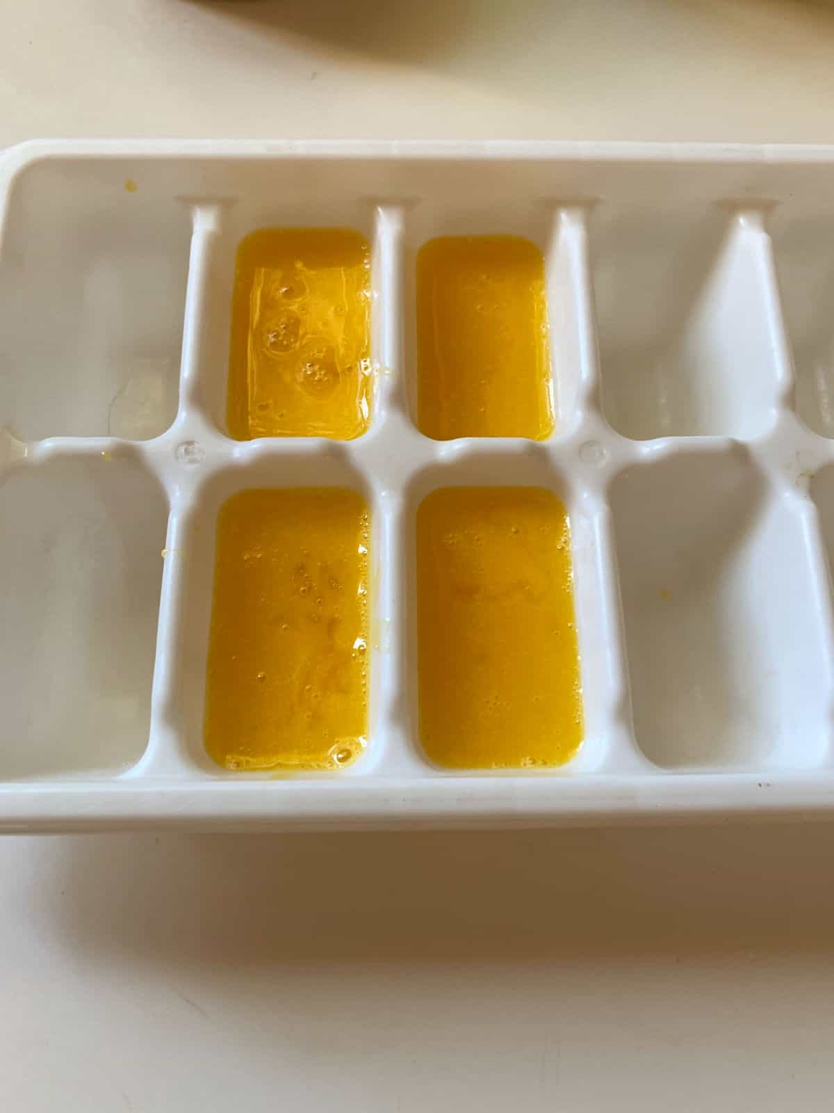 Beaten egg yolks in an ice cube tray.