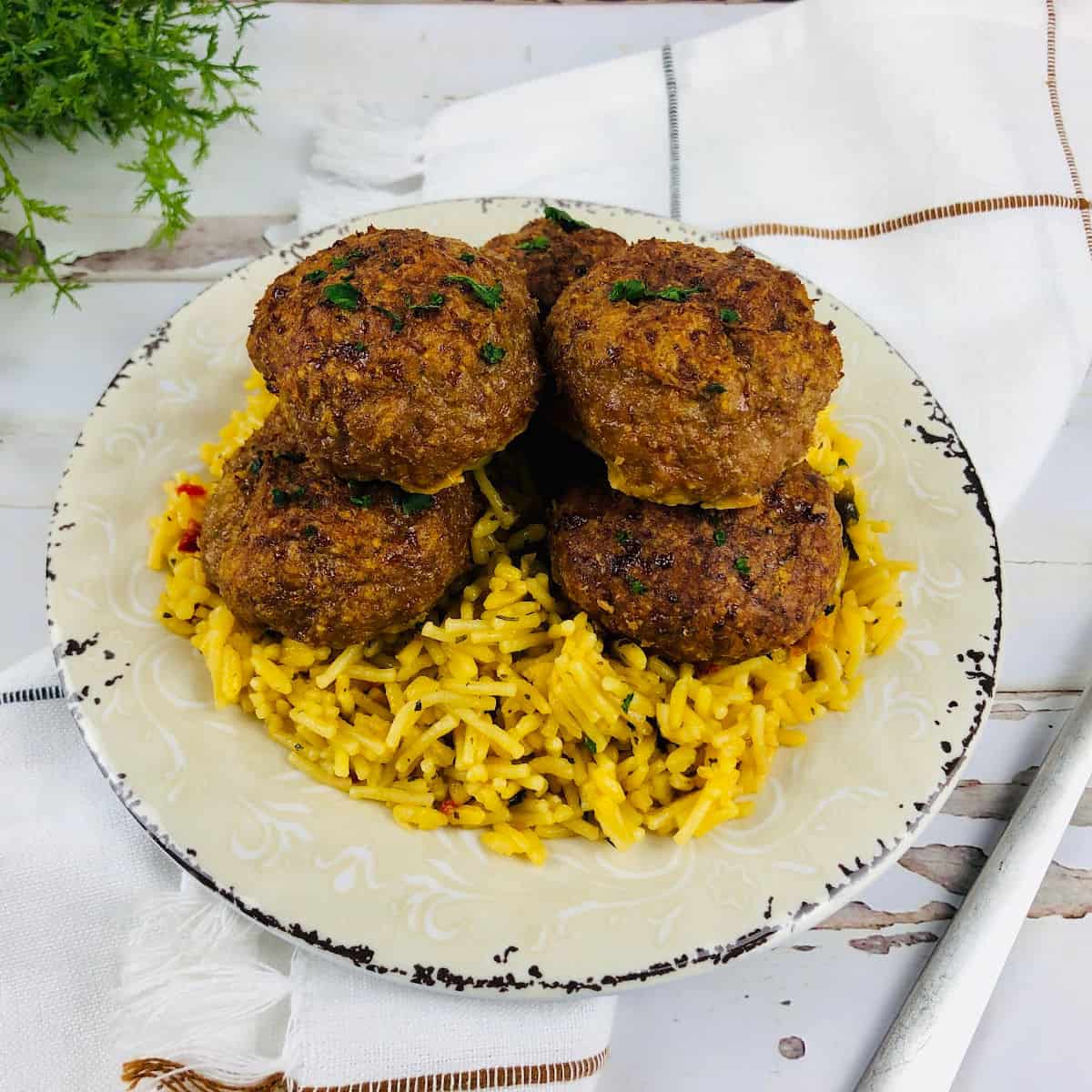 Meatballs on top of rice on a white plate.