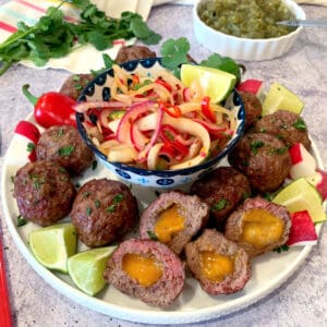 Mexican meatballs stuffed with cheese on a white plate.