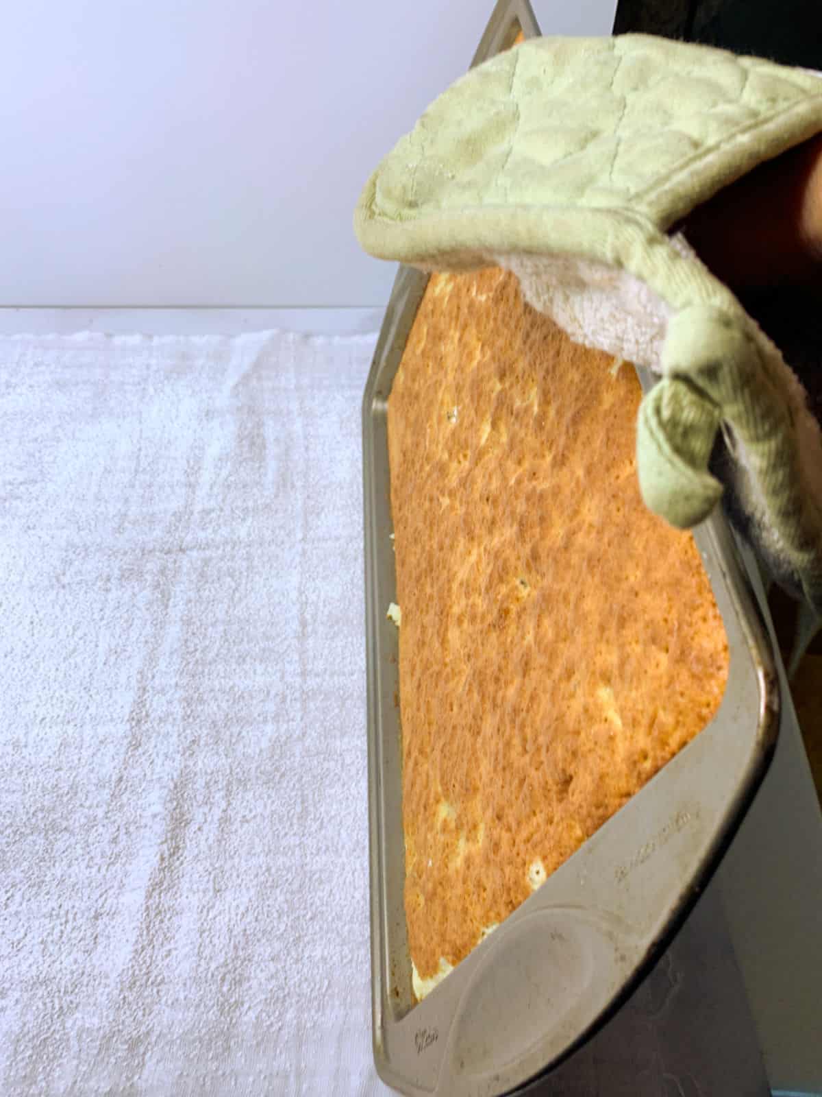 Flipping a cake out of the pan onto a towel.