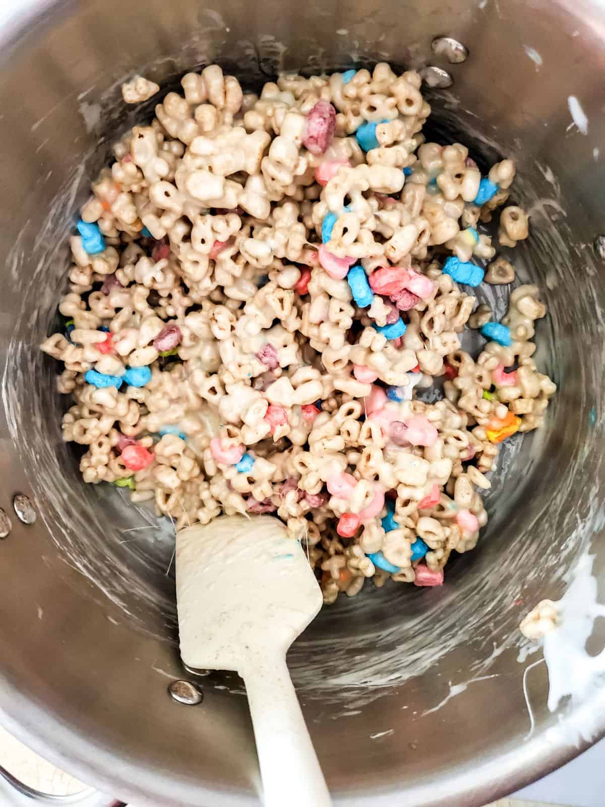 Mixing Lucky Charm cereal in a silver bowl.