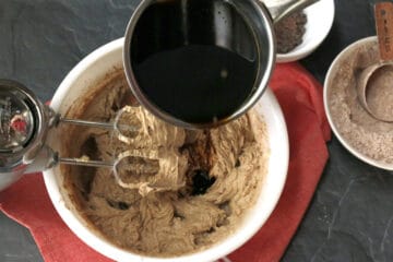 Pouring hot molasses into a chocolate batter.