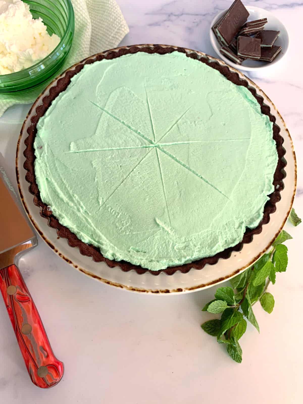 A mint tart with Andes candies and whipped cream next to it.