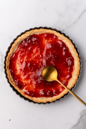 Strawberry jam in a baked tart shell in a tart pan.