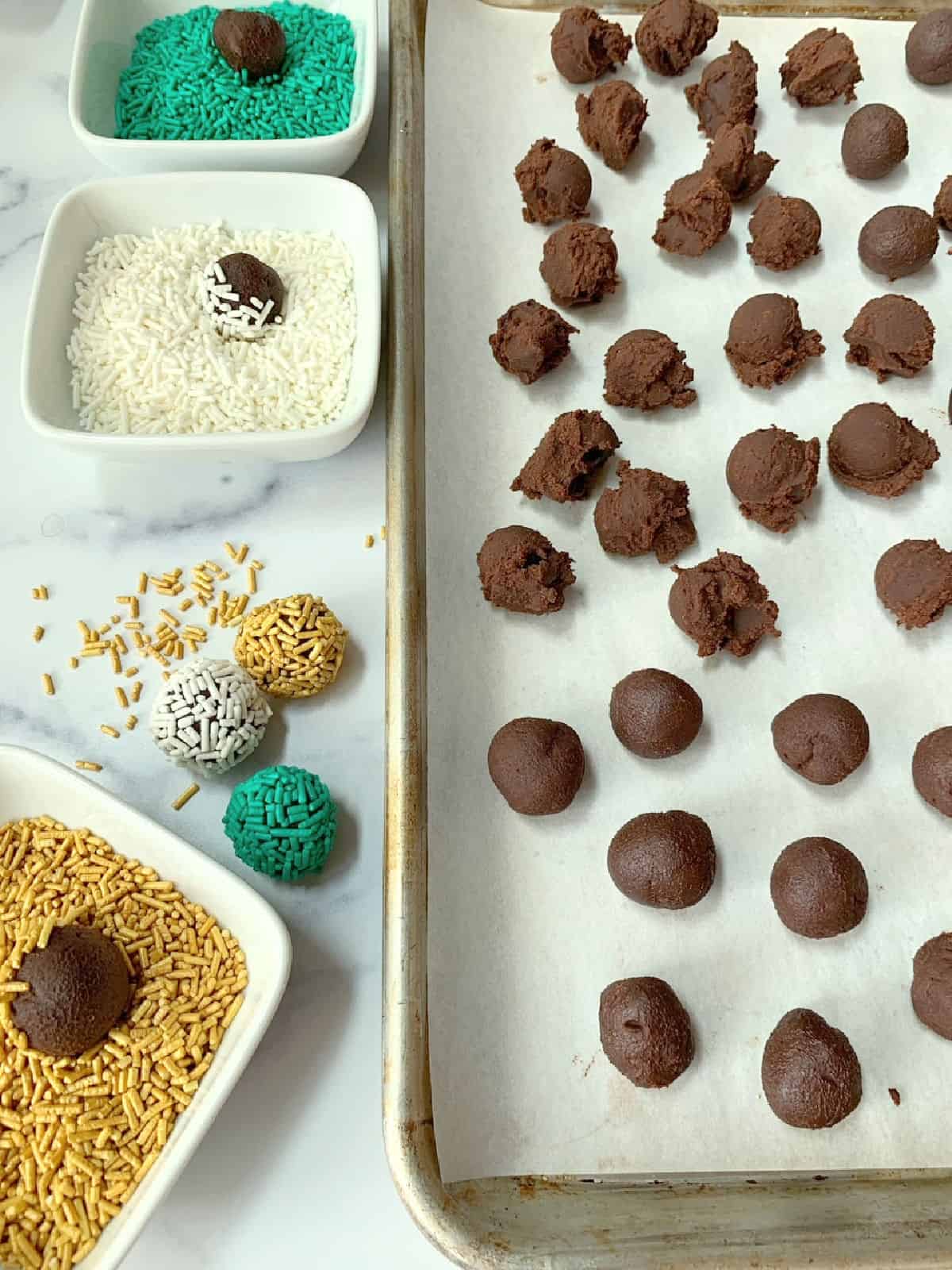 A sheet pan with chocolate ganache balls, and chocolate in sprinkles.