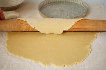 Rolling out a pastry dough with a wood rolling pin.