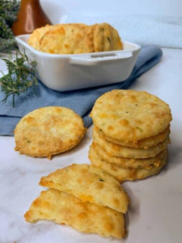 Cheddar crackers stacks on a board and in a white casserole dish.