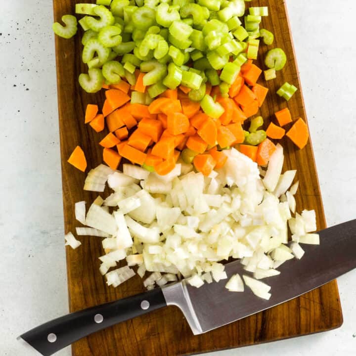 Chopped vegetables on a cutting board with a knife.
