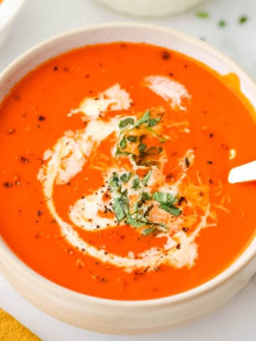 A bowl of tomato soup with a spoon.