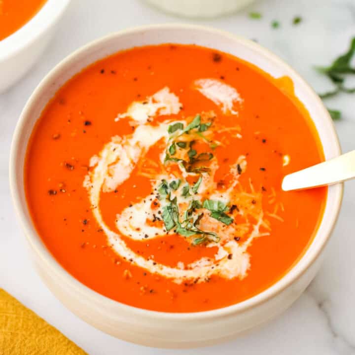 A bowl of tomato soup with a spoon.