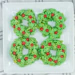 Four green christmas wreath cookies on a plate.