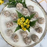 Coconut energy balls on a plate with yellow flowers.