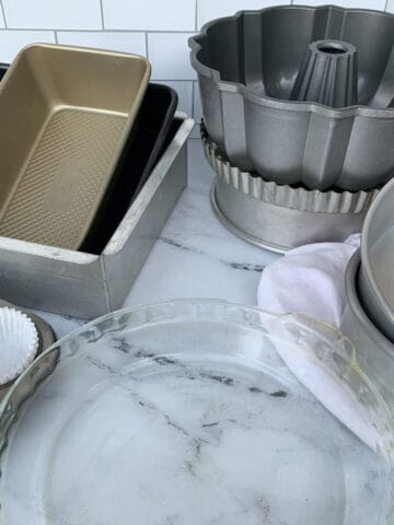 Baking pans, muffin tins, and cake pans on a counter.