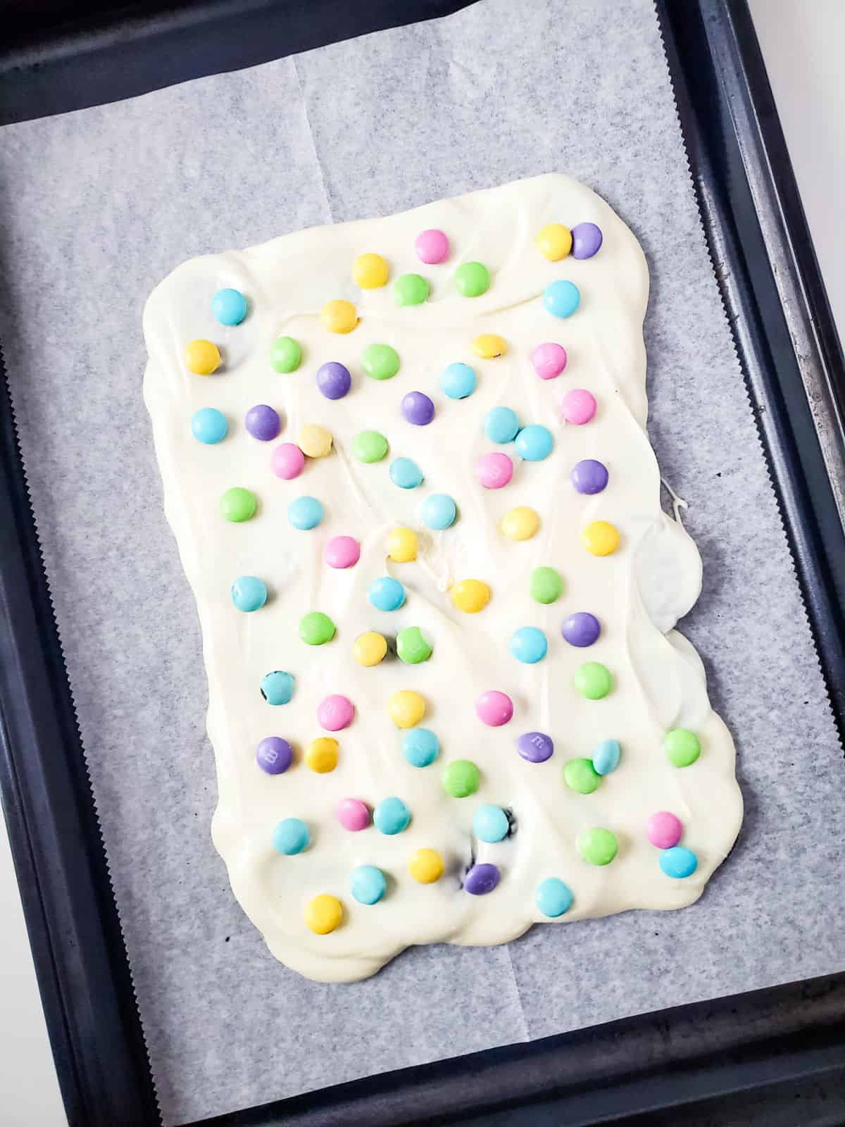 White chocolate with colorful candies on a baking sheet.
