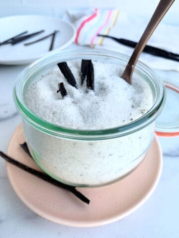 A bowl of vanilla bean sugar with vanilla pods in it.