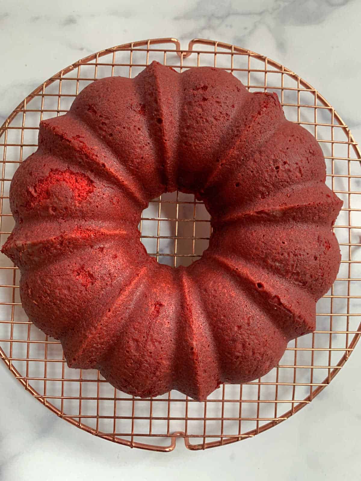A red velvet bundt cake on a cooling rack.