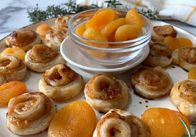 A plate of pastries and a bowl of dried apricots.