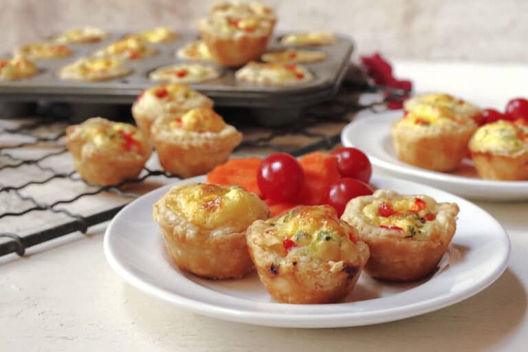 A tray of mini quiches with fruit and vegetables on it.