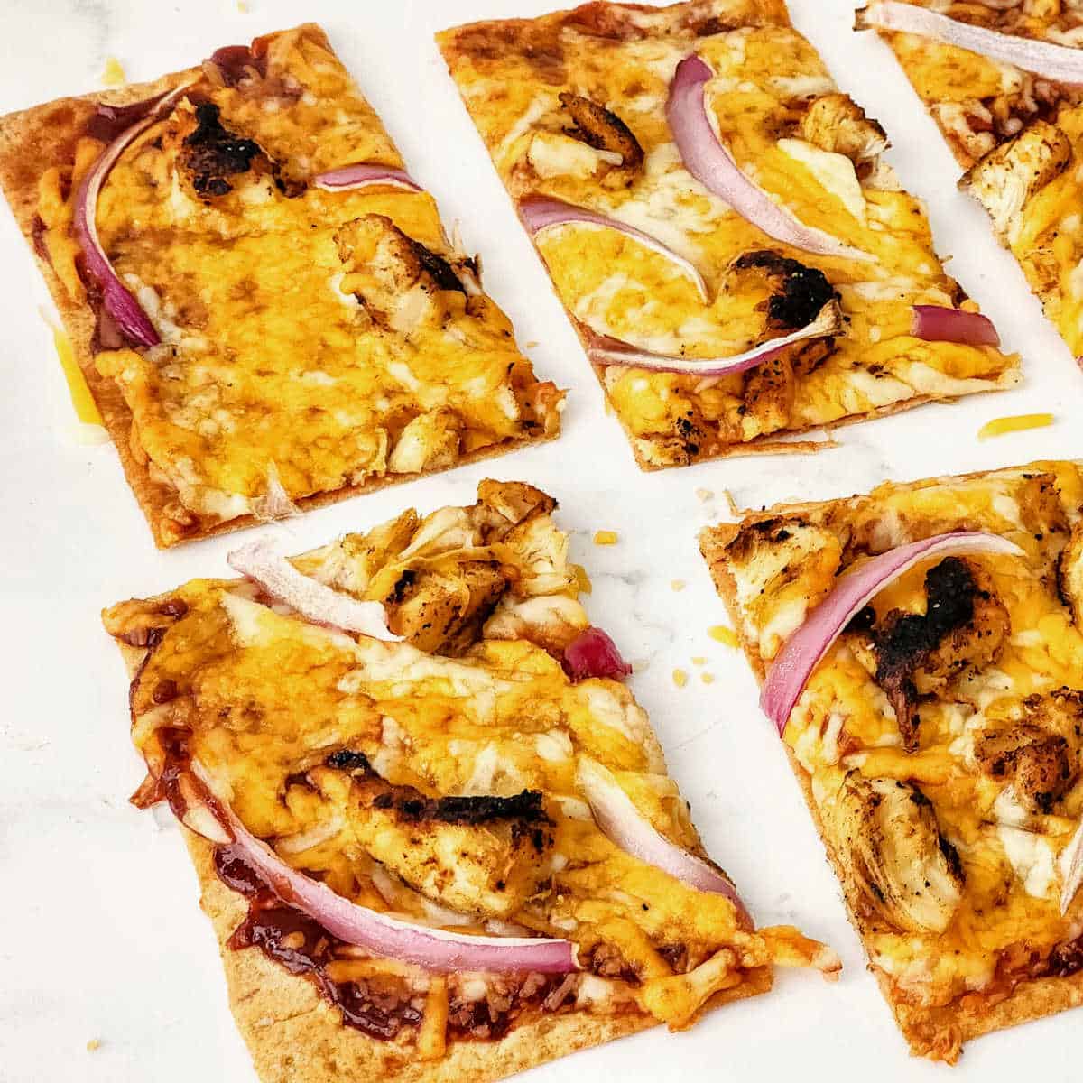 Baked chicken pizza with red onions cut in squares.