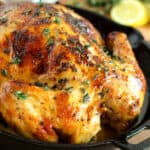 A roasted chicken in a cast iron skillet with lemons.