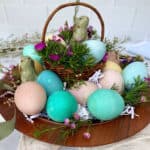 Colorful easter eggs in a basket on a wooden table.