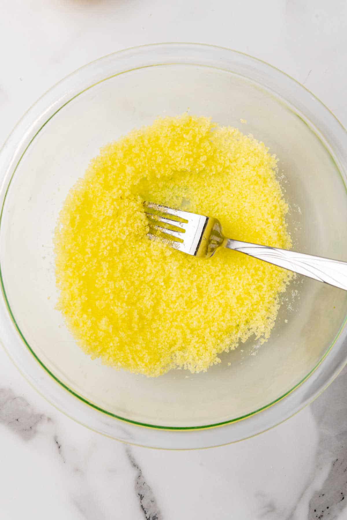 Yellow sanding sugar in a clear glass bowl.