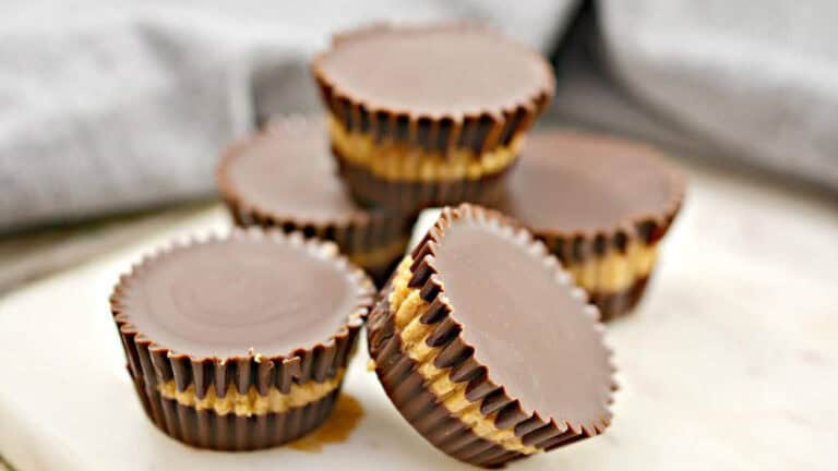 Five chocolate and peanut butter cups stacked on a white surface.