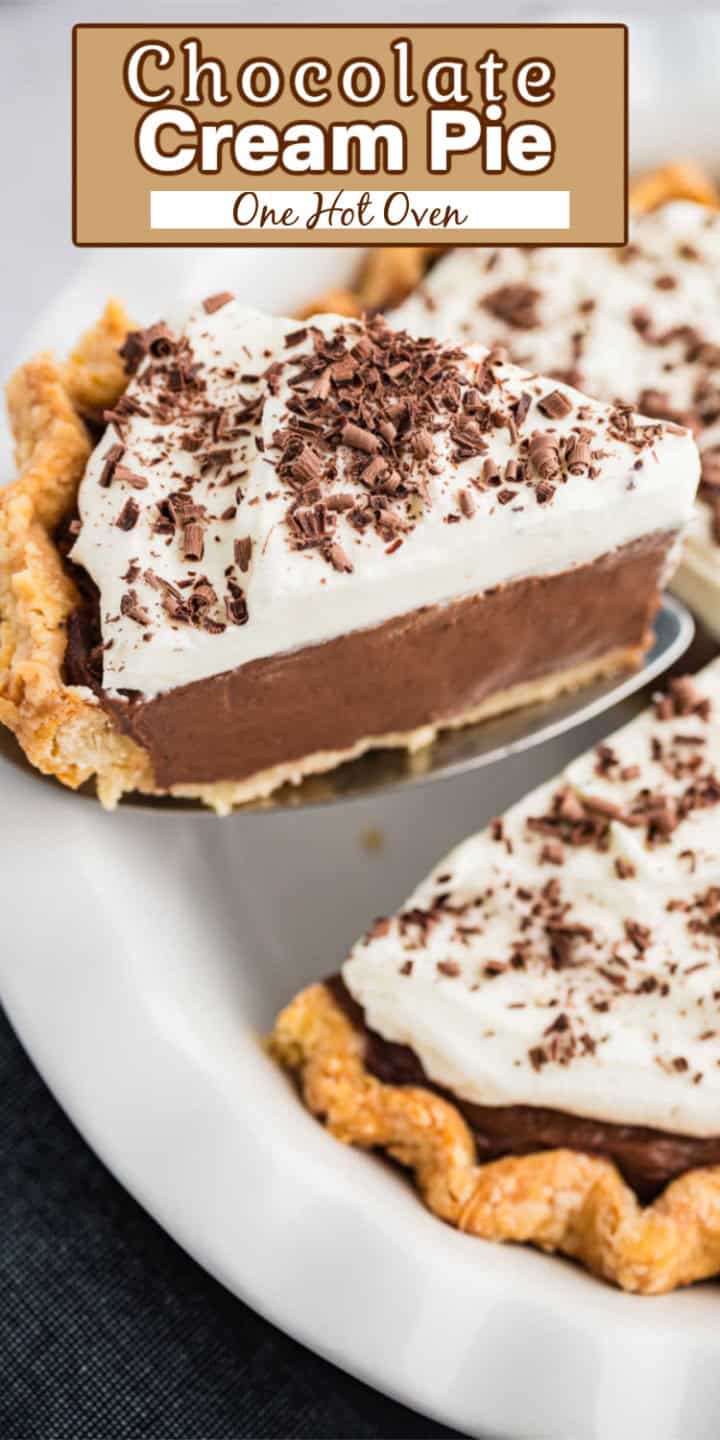 A slice of chocolate cream pie topped with whipped cream and chocolate shavings is being served from a white plate.