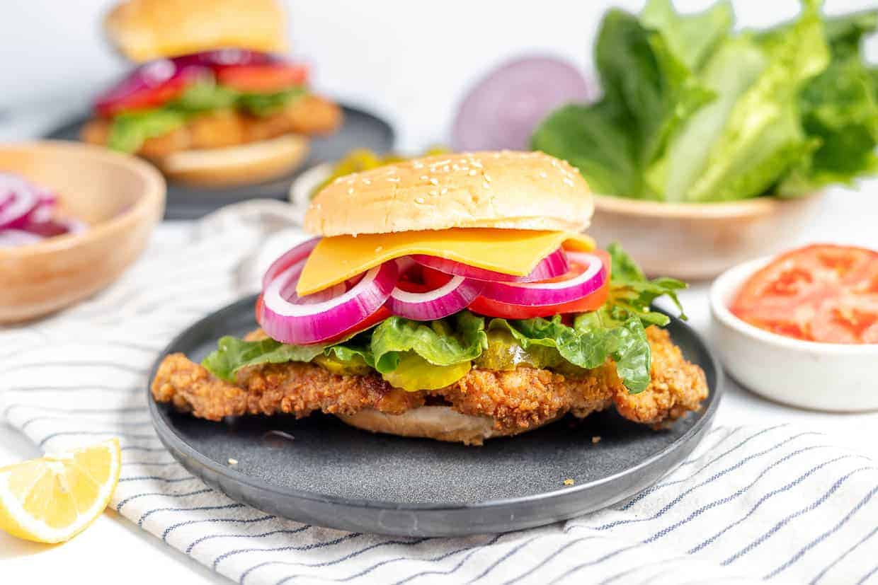 Crispy pork tenderloin sandwich on a black plate.