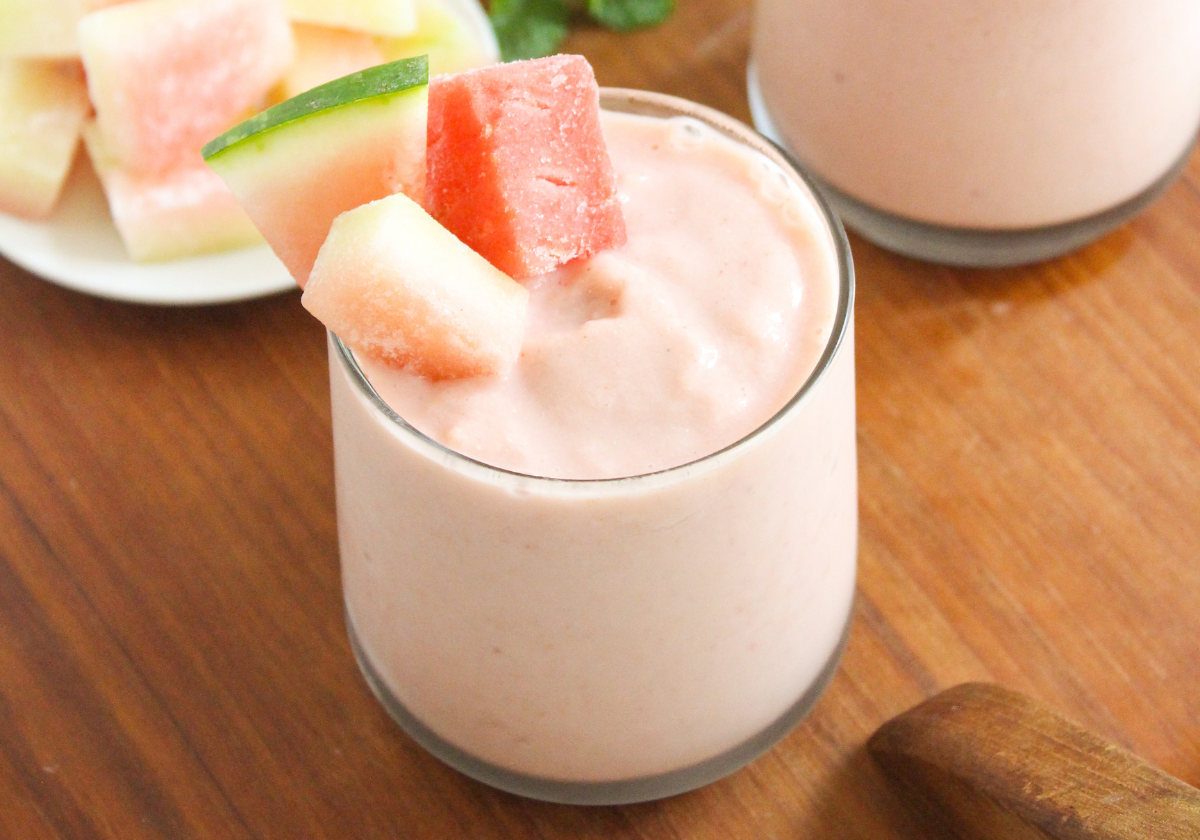 A short glass filled with watermelon peach smoothie with cubed watermelon on top.