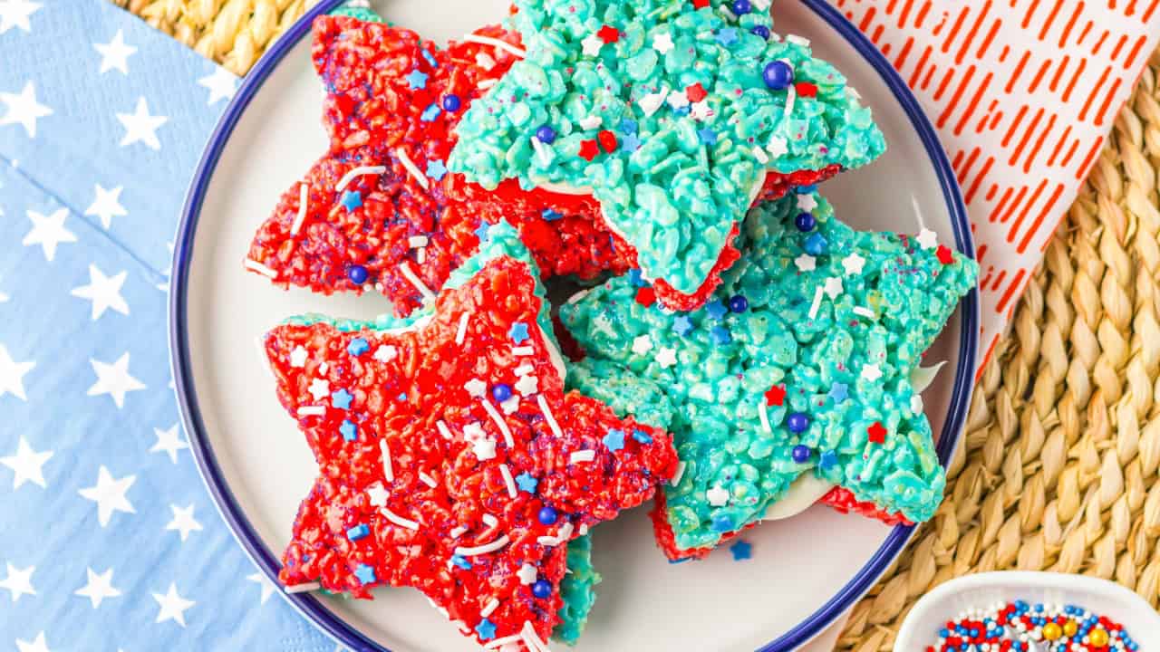 Red white and blue star shaped rice krispie treats stacked on a white plate.