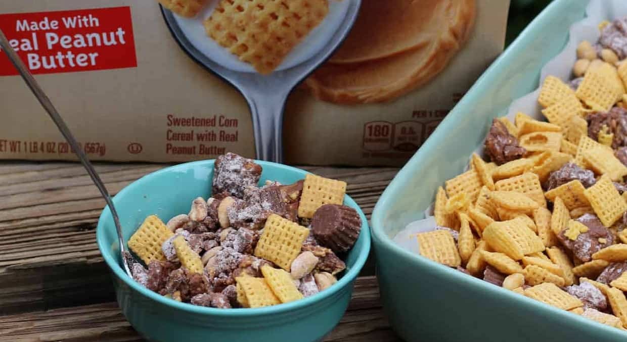 Teal bowl of chex party mix next to a cereal box and casserole dish.